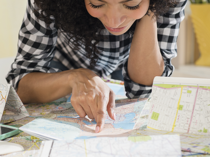 Woman with black & white checked shirt reading a travel map